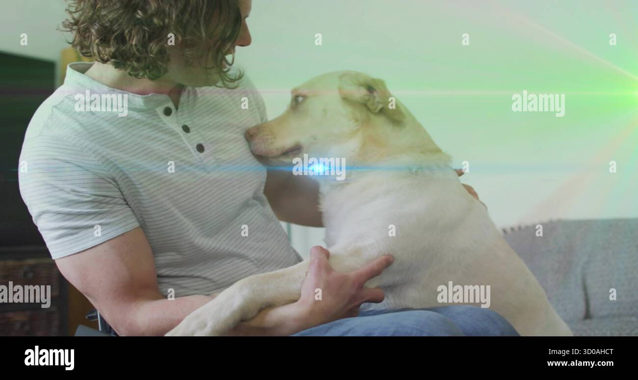 Coccolante in Henley e jeans che tengono un cane bianco-giallastro in soggiorno, con armadietto TV Foto Stock