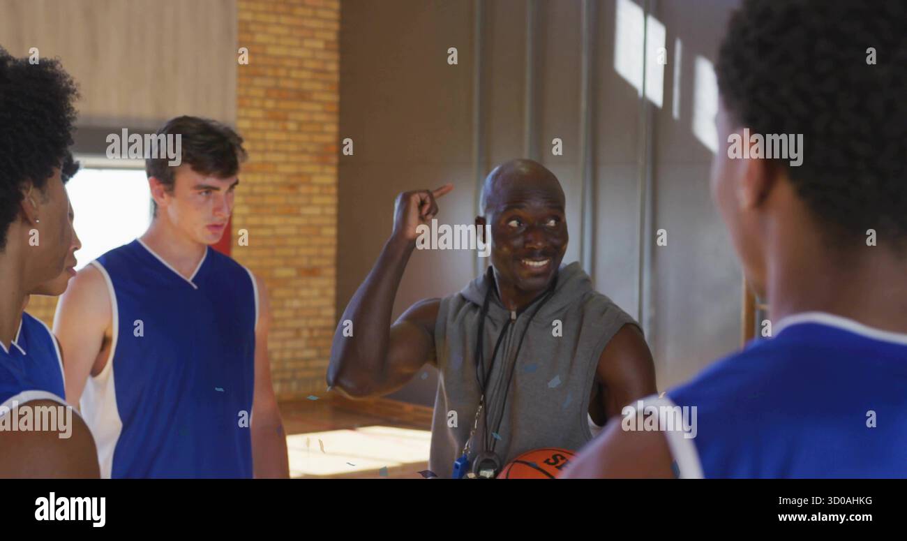 Allenatore senior in piedi che si rivolge ai giocatori del campo della palestra delle scuole superiori, con pallacanestro e fischio Foto Stock