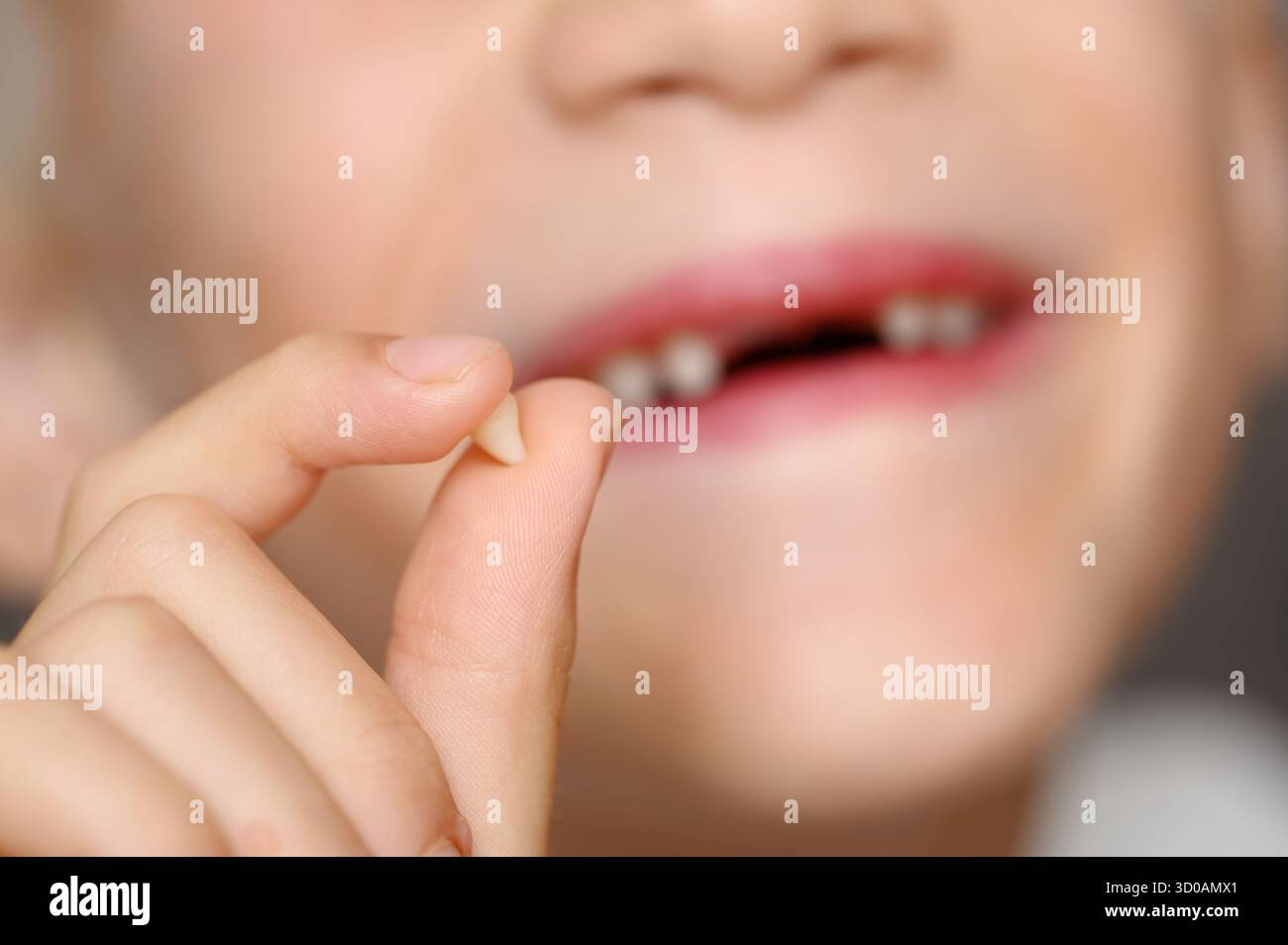Il bambino mostra il dente del bambino, tenendolo in mano e sorridendo, primo piano. Il ragazzo mostra con orgoglio un piccolo dente anteriore mancante. Nozione di odontoiatria pediatrica, Foto Stock