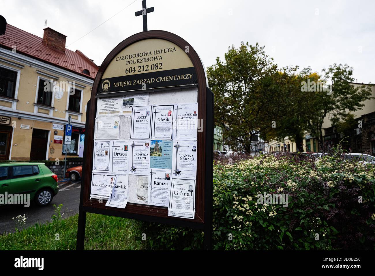 Tarnow, Polonia - 10 ottobre 2025: Bacheca del cimitero a Tarnow, Polonia, piena di manifesti funerali accanto a una strada tranquilla e agli edifici. Foto Stock