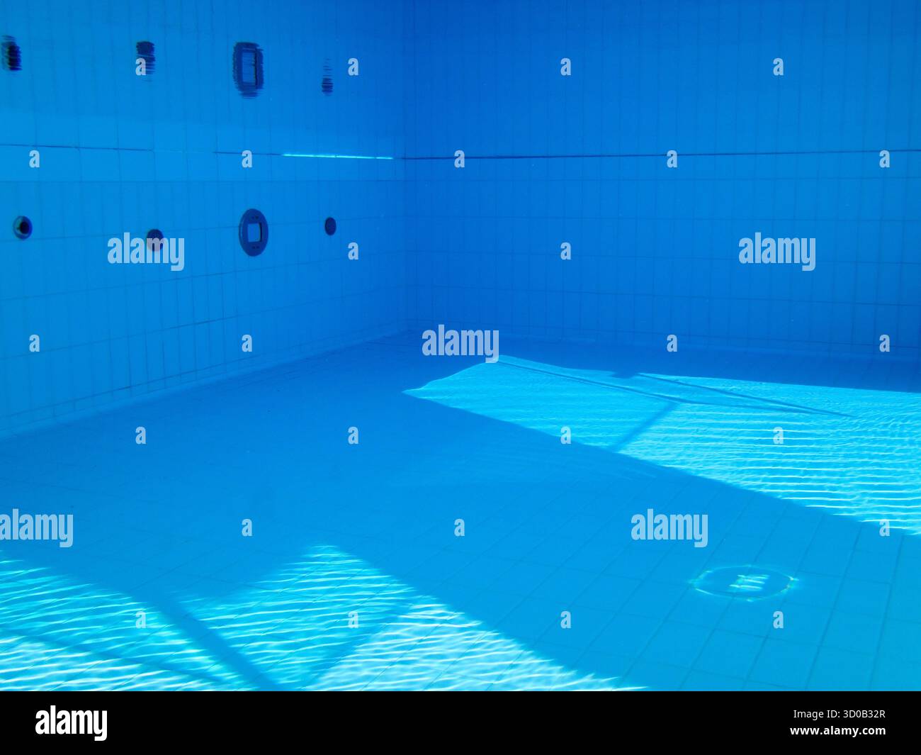 Vista subacquea di una piscina vuota piastrellata con luce solare e ombre Foto Stock