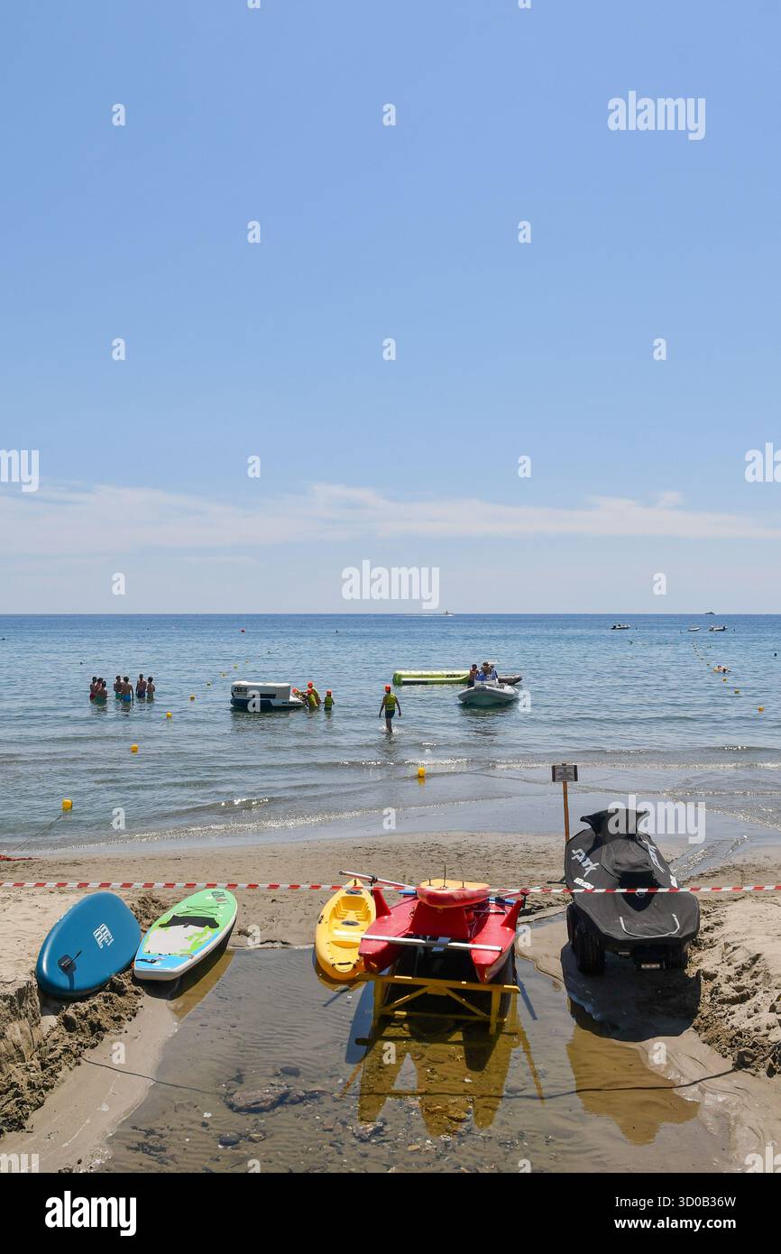 Spiaggia con varie attrezzature per sport acquatici (stand-up paddleboard, pedalò, kayak, gommoni gonfiabili), Alassio (Savona) Liguria, Italia Foto Stock