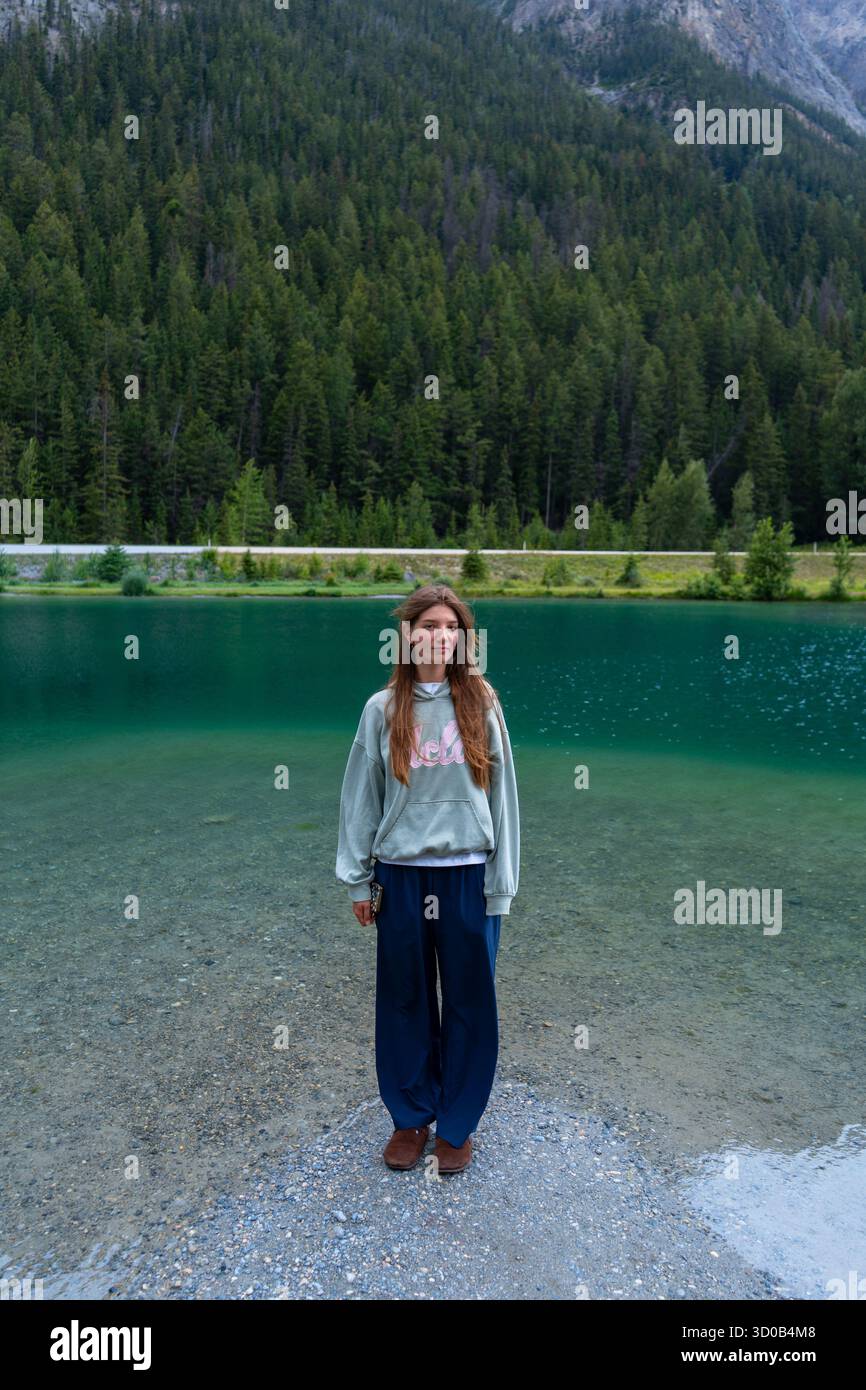 Una ragazza in natura vicino al lago, indossa un maglione e pantaloni. Campo, BC Foto Stock