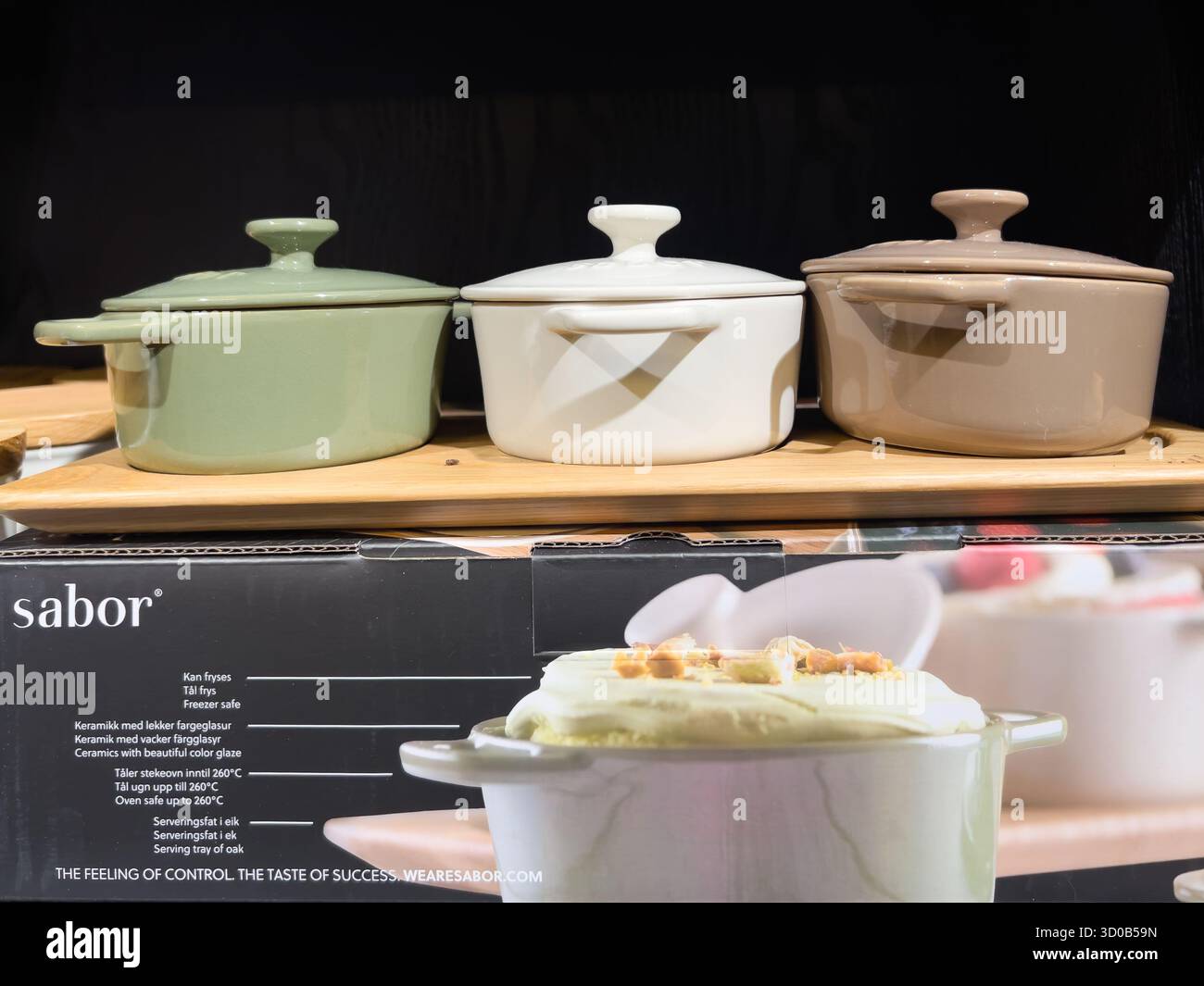 Karlstad, Svezia - 18 ottobre 2025: Pentole di ceramica colorata in verde, bianco e marrone disposte su scaffale in legno, perfette per cucinare e servire Foto Stock