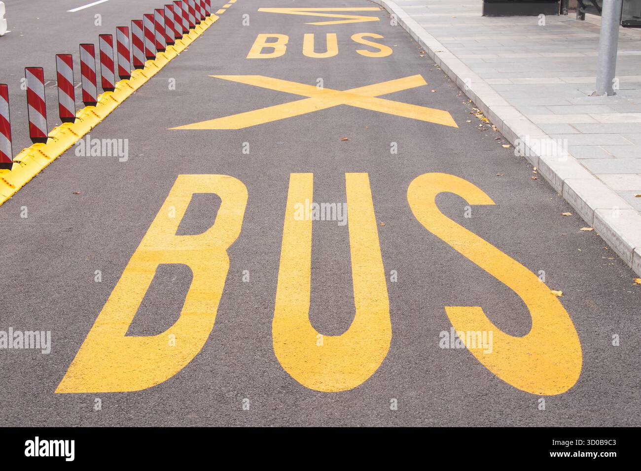 Segnaletica stradale gialla alla fermata dell'autobus e divisori di corsia fluorescenti di sicurezza su strade vuote della città Foto Stock