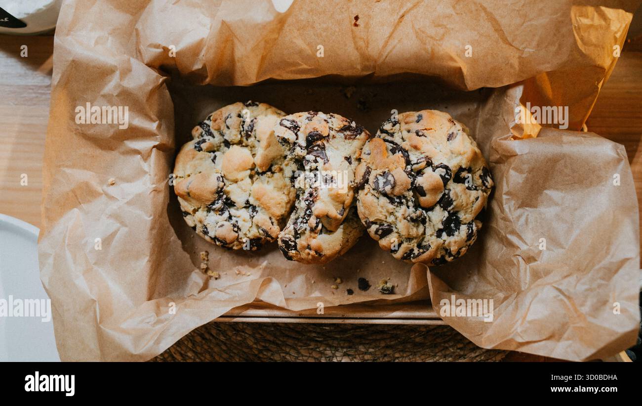 Tre biscotti con scaglie di cioccolato sono seduti in un sacchetto di carta marrone. I cookie vengono posizionati in modo che si tocchino tra loro Foto Stock