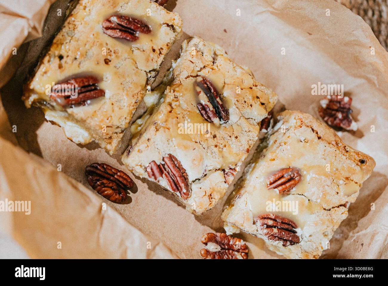 Tre deliziose tavolette da dessert con una copertura di noci sono disposte sopra un sacchetto di carta marrone. Le barre da dessert sono tagliate in tre parti uguali e sono pla Foto Stock