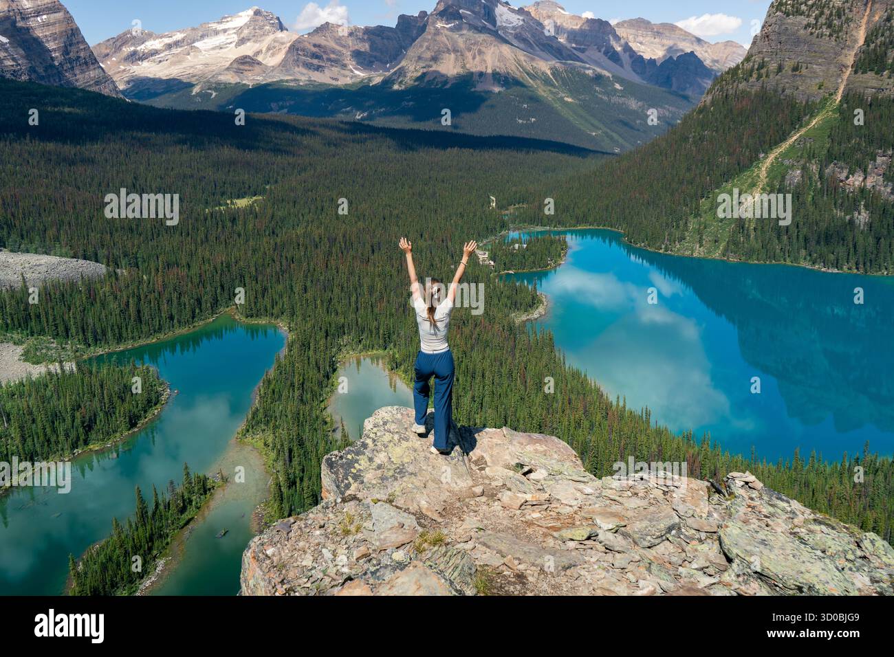 Trionfo sulla vetta: La donna celebra il raggiungimento della vetta della montagna con vista. Lago Ohara, British Columbia Foto Stock