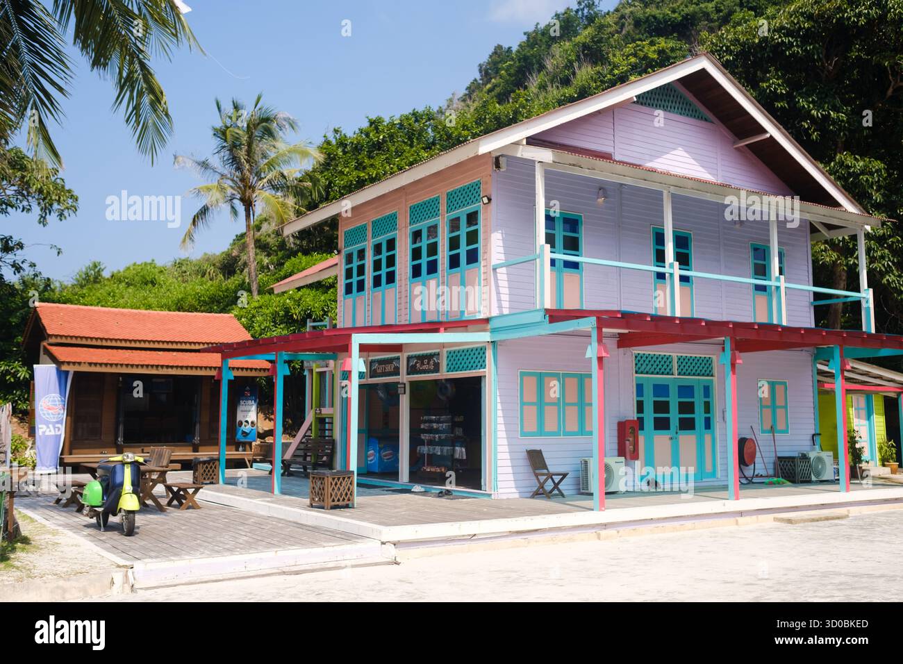 Isola di Redang. Malesia. 29 luglio 2025. Un edificio colorato vicino a lunga spiaggia con posti a sedere all'aperto in un ambiente tropicale in una luminosa giornata di sole. Foto Stock