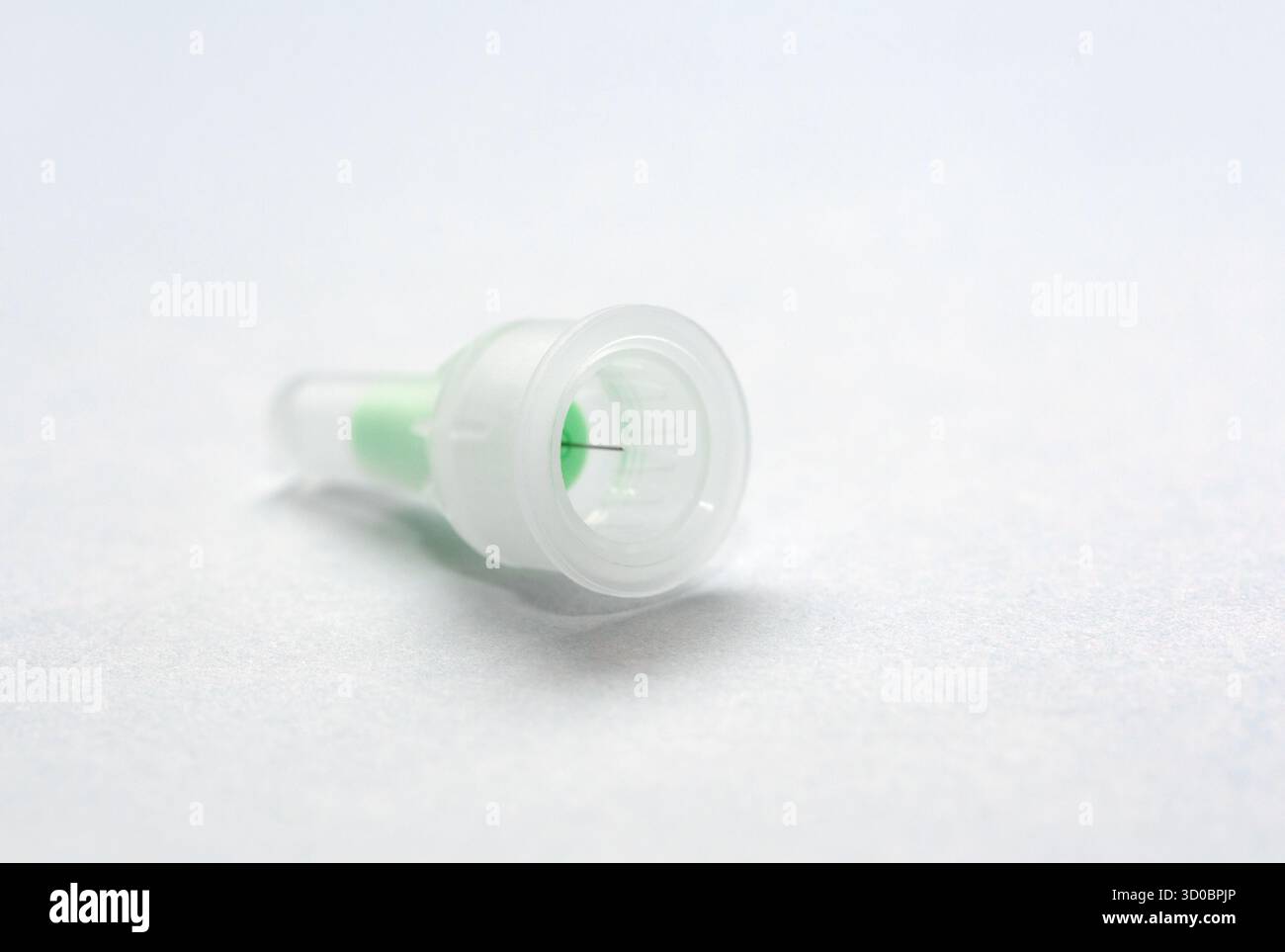 Primo piano di una punta di siringa medica con un componente interno verde, posizionato su uno sfondo chiaro, evidenziandone il design dettagliato e l'uso pratico Foto Stock