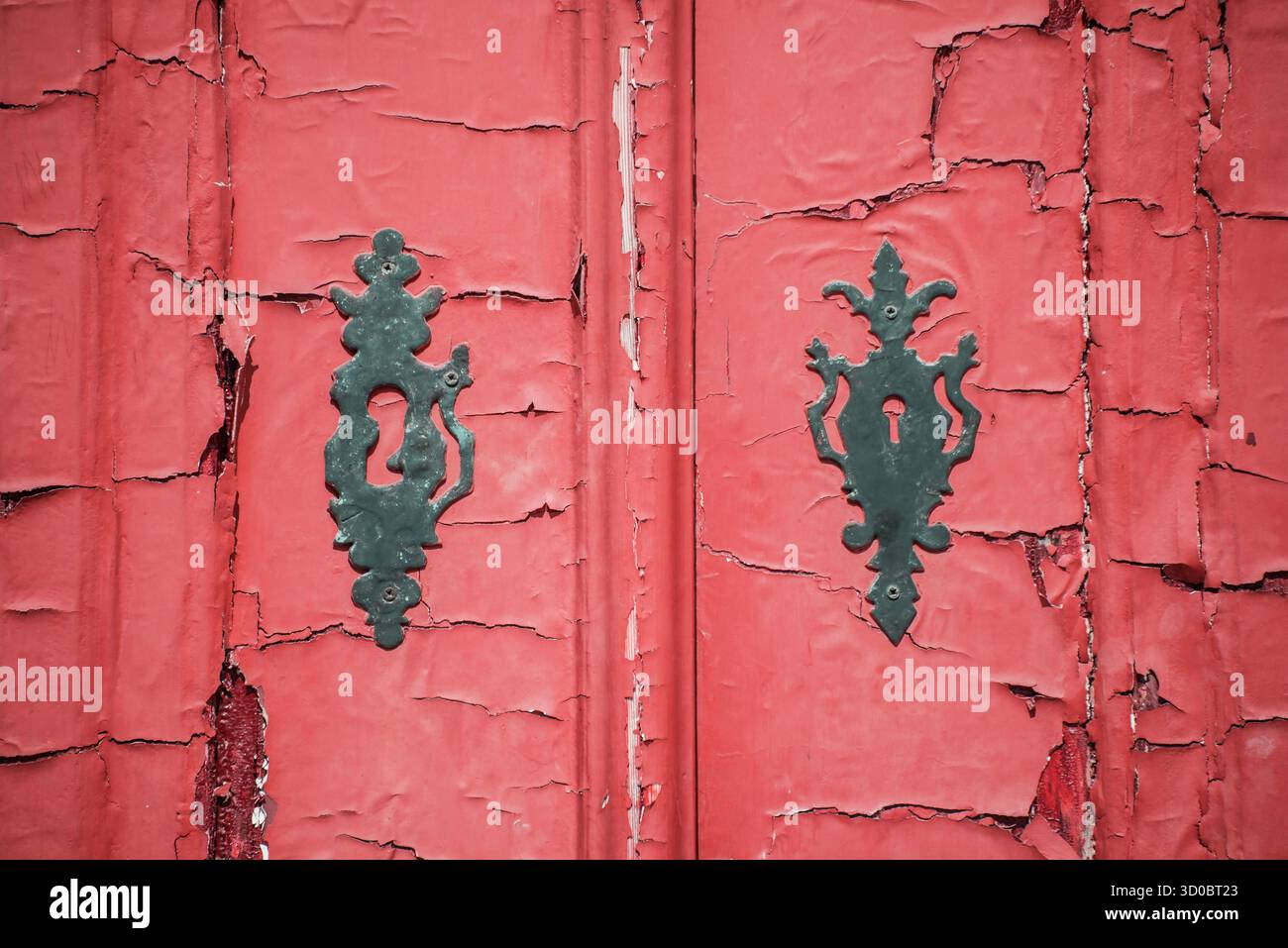 Piastre di bloccaggio e vernice rossa spaccata e spaccata su una vecchia porta in Portogallo Foto Stock