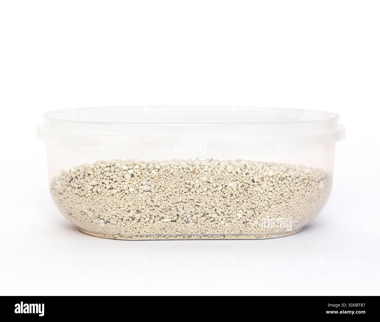 Il contenitore trasparente contiene piccoli granuli bianchi di lettiera per gatti, sottolineando un design pulito ed elegante, adatto per lo stoccaggio e l'organizzazione Foto Stock