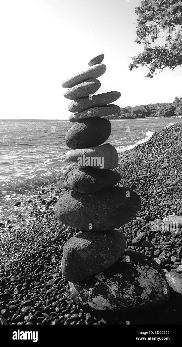 Vista in bianco e nero di una torre di ciottoli impilata sulla riva lungo la costa nord-est di Bali, evidenziando texture e contrasti nella zona tropicale Foto Stock