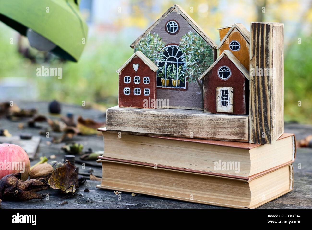 Una scena stravagante con case in legno in miniatura arroccate su una pila di vecchi libri, creando una composizione affascinante e nostalgica. Foto Stock