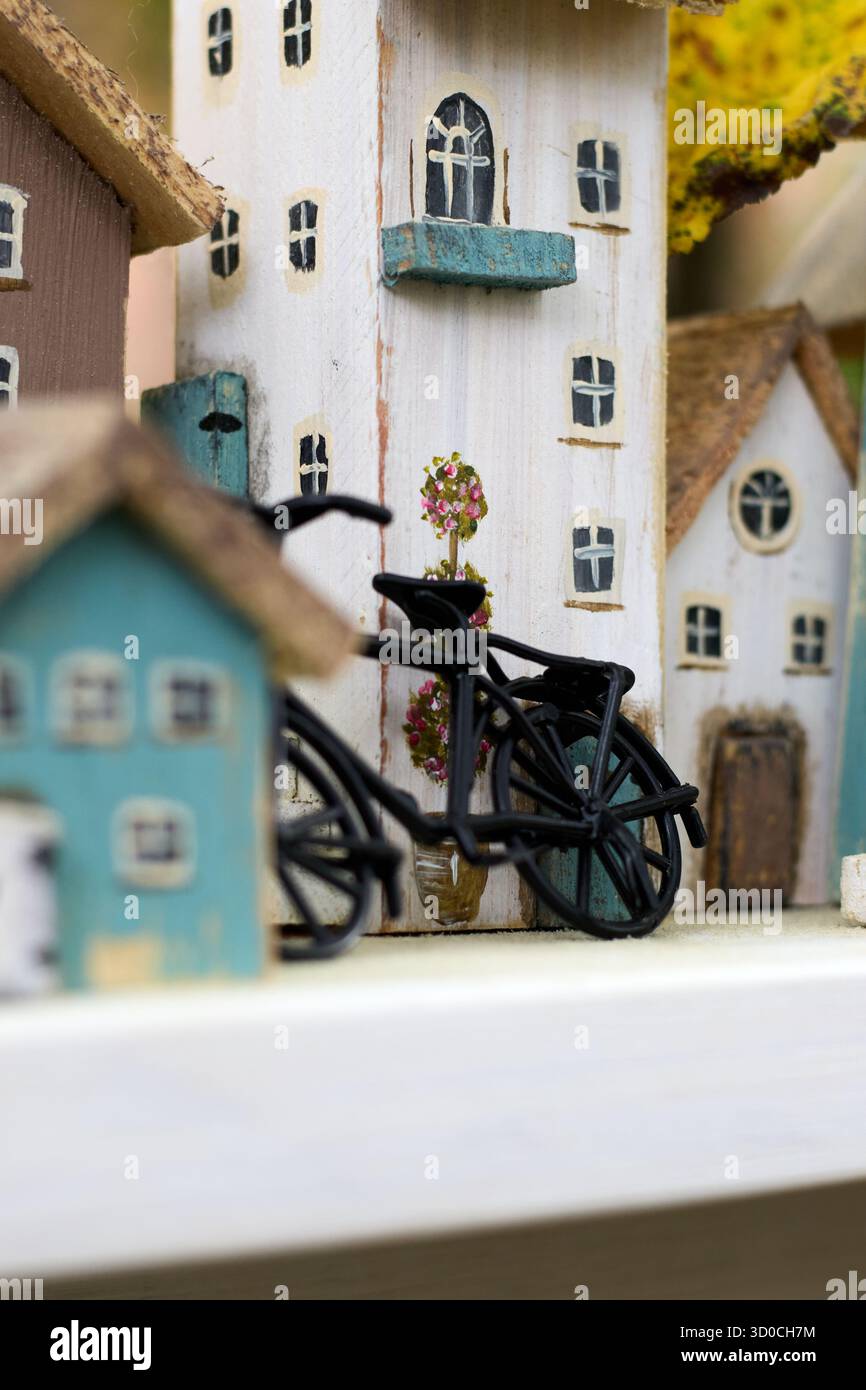 Un affascinante villaggio in miniatura con case in legno e una piccola bicicletta nera, che crea un'atmosfera stravagante e nostalgica. Foto Stock