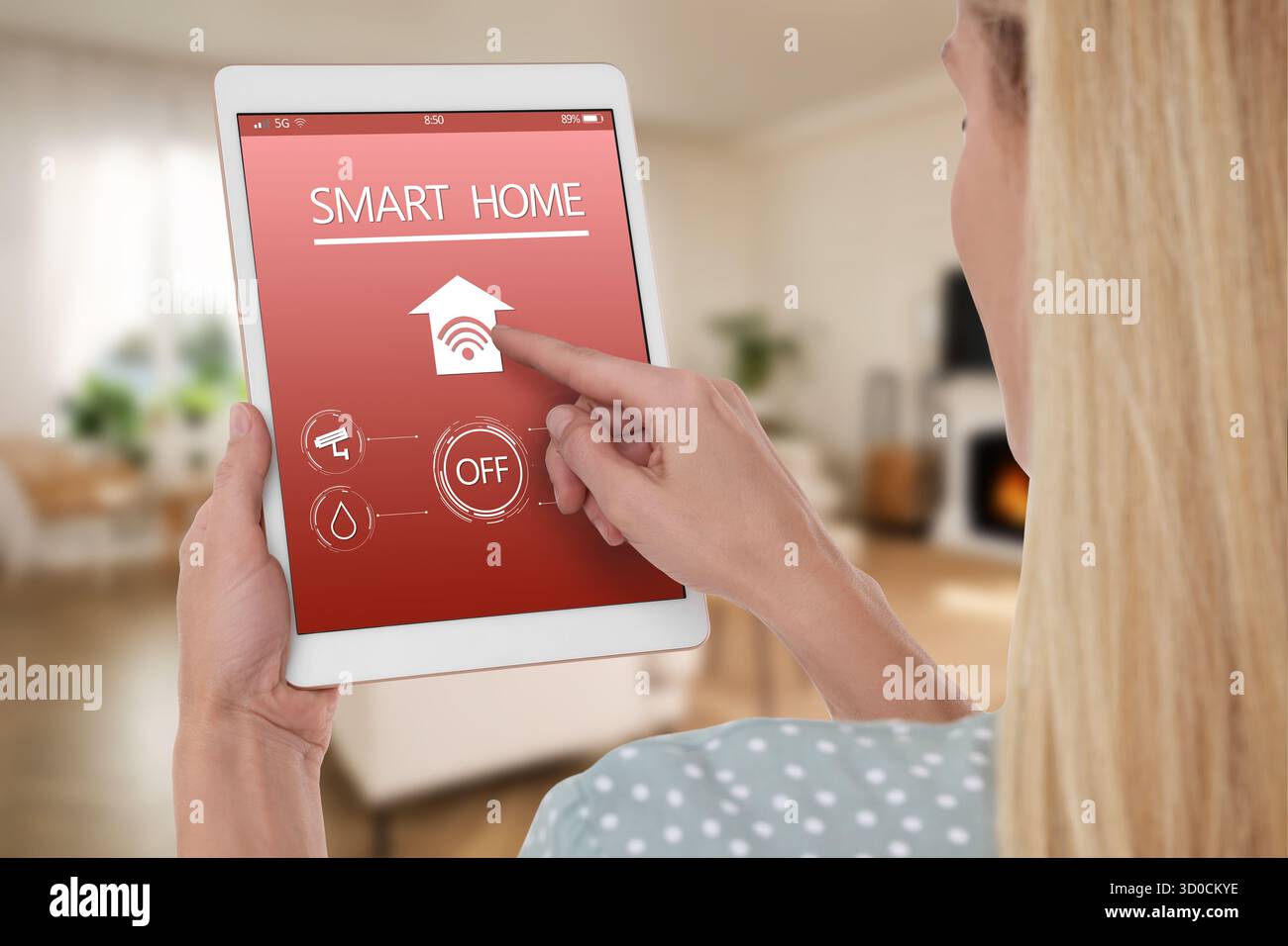 Donna che usa un'app per la casa intelligente su un tablet per controllare le caratteristiche della casa, primo piano Foto Stock
