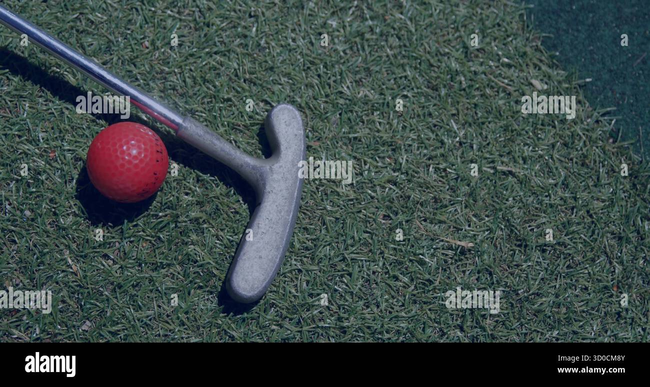 Testa di putter da golf in argento e palla da golf rossa su putting green rifinito, con tappetino sintetico Foto Stock