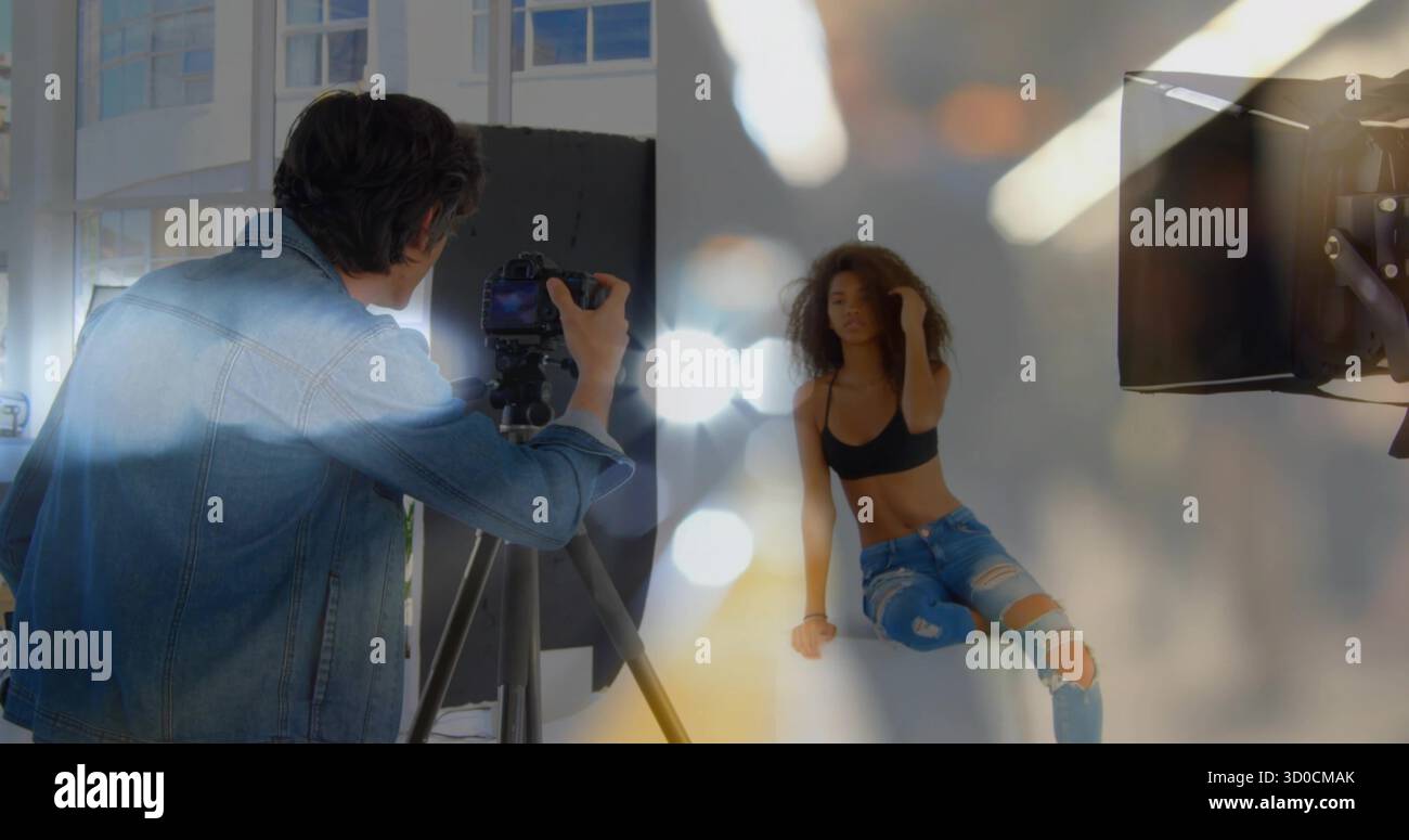 Posa di un modello con la parte superiore del ritaglio, jeans strappati in studio, treppiede DSLR regolabile da fotografo, softbox Foto Stock