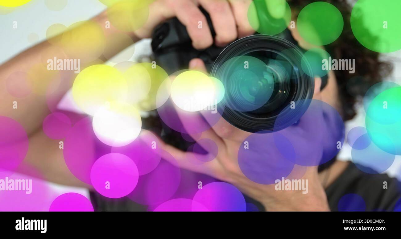 Tenere in mano l'obiettivo di regolazione del fotografo DSLR in studio, con copriobiettivo e sovrapposizione bokeh colorata Foto Stock