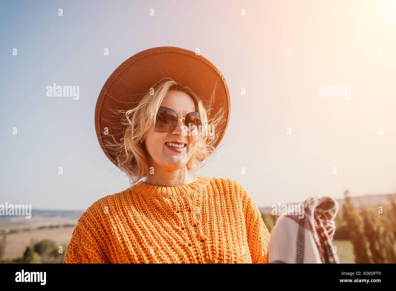 Donna sorridente con cappello marrone e occhiali da sole Foto Stock