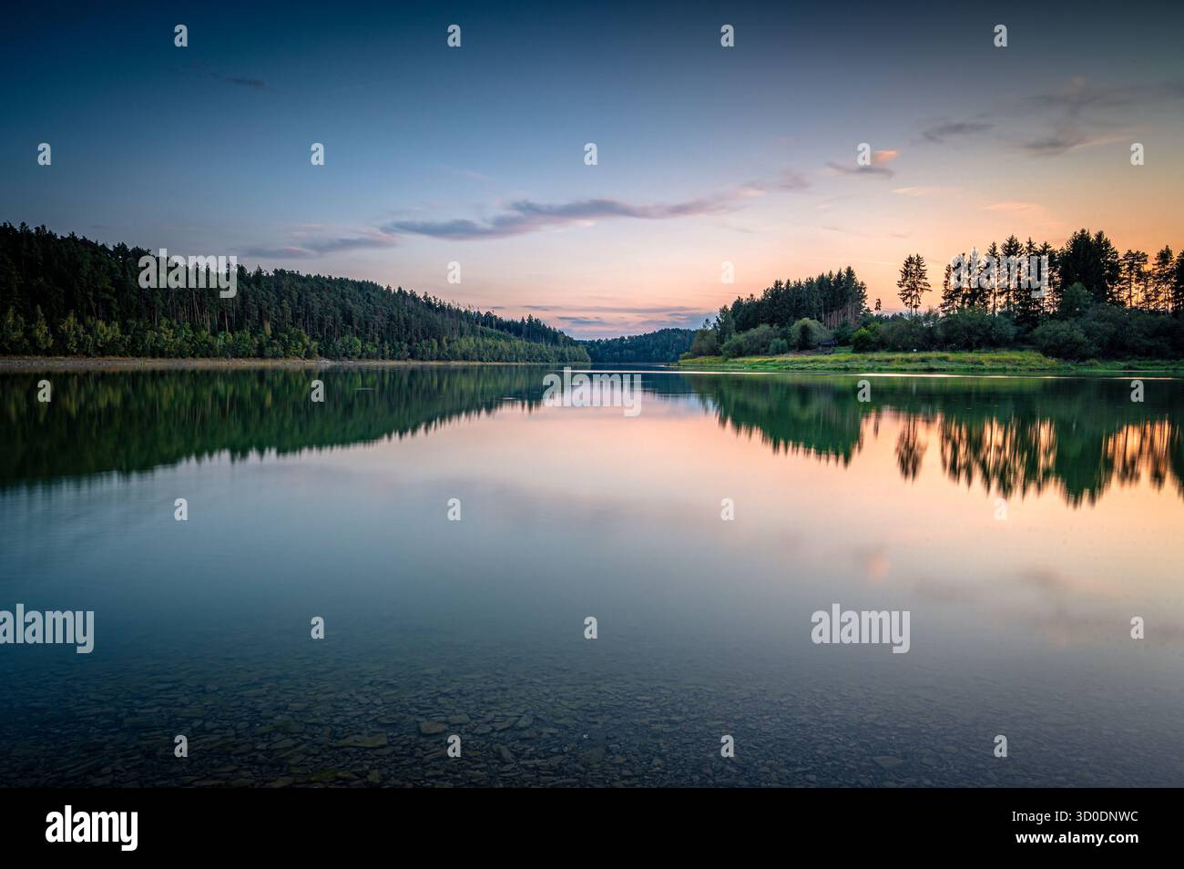 Tranquillo paesaggio acquatico serale con foresta e dolci riflessi del cielo, serbatoio Zeulenrodaer Meer, tribù Zeulenroda, Turingia, Germania Foto Stock