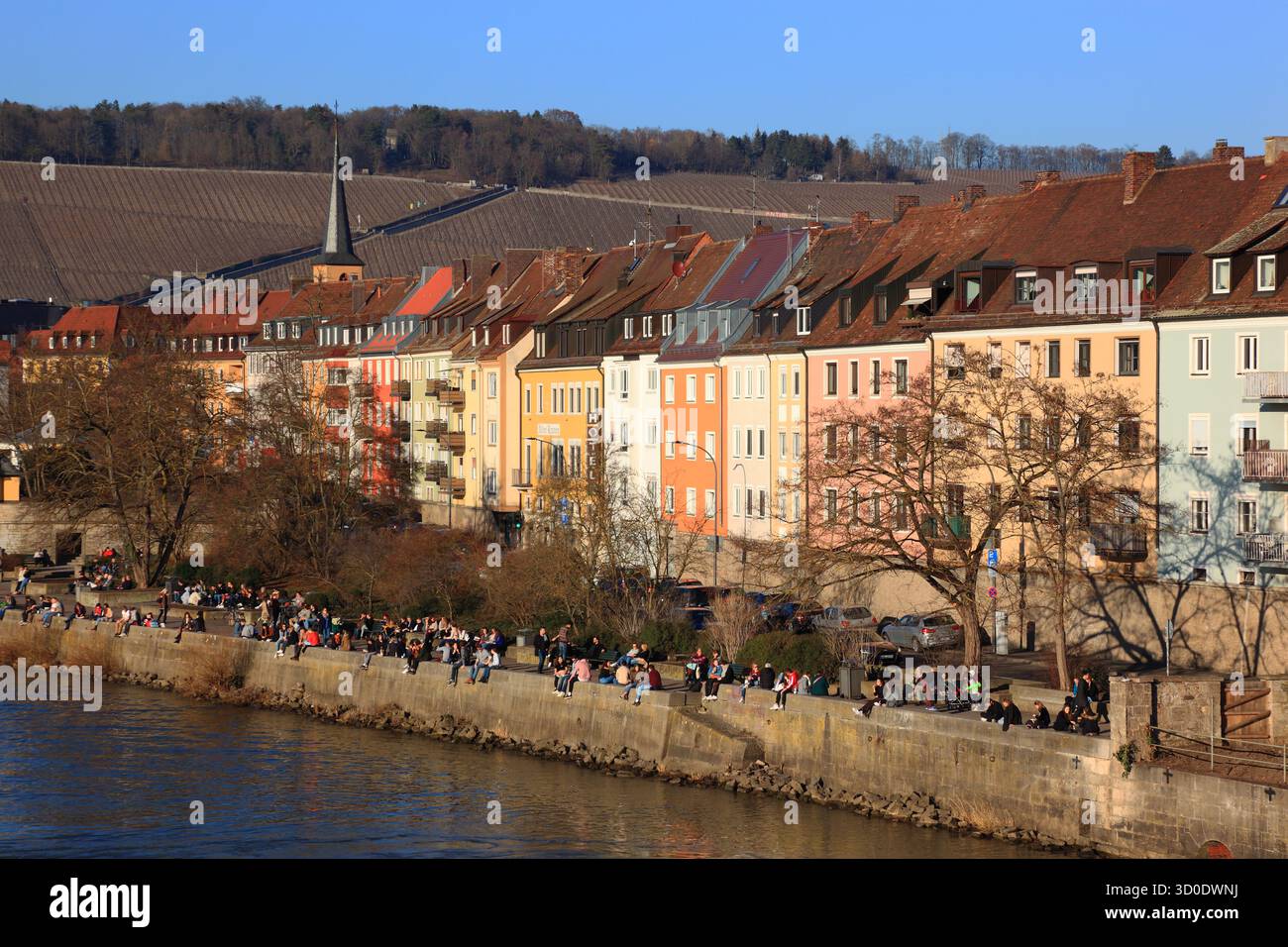 La gente gode del primo sole primaverile lungo le vecchie case cittadine sul fiume meno, Würzburg, bassa Franconia, Baviera, Germania Foto Stock