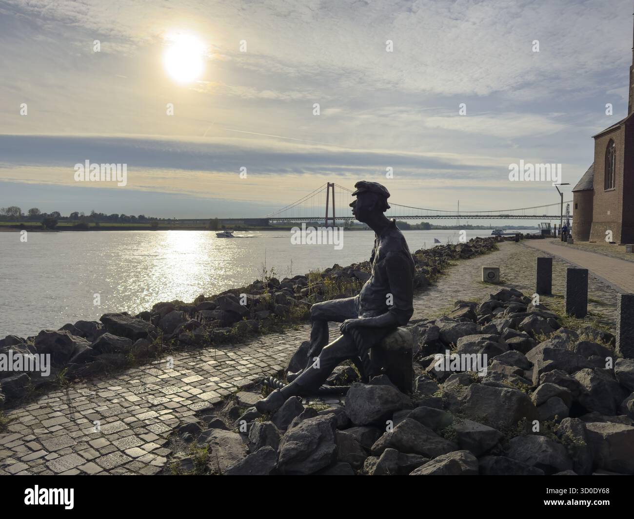 Foto con malinconia atmosfera della scultura in bronzo Poortekerl che guarda il Reno in attesa dello scarico della nave, navigazione sul Reno navigazione interna, reminiscenza Foto Stock