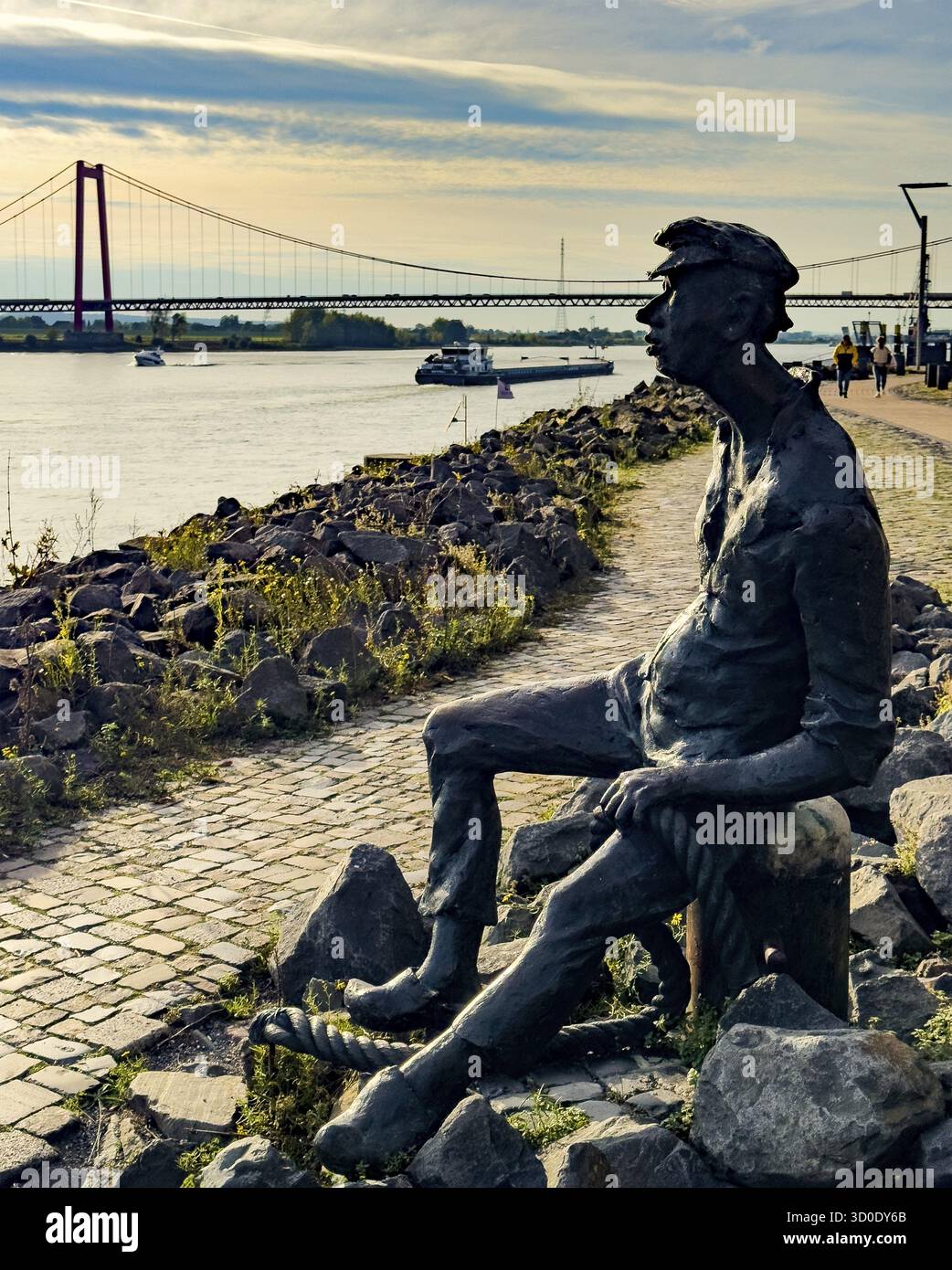 Foto con malinconia atmosfera della scultura in bronzo Poortekerl che guarda il Reno in attesa dello scarico della nave, navigazione sul Reno navigazione interna, reminiscenza Foto Stock