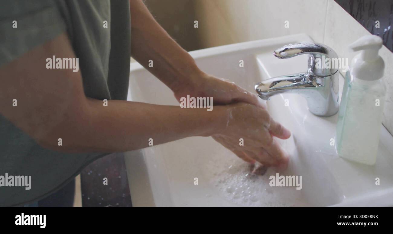 Donna che lava le mani sotto il rubinetto cromato corrente nel lavandino del bagno di casa con dispenser di sapone e suds Foto Stock