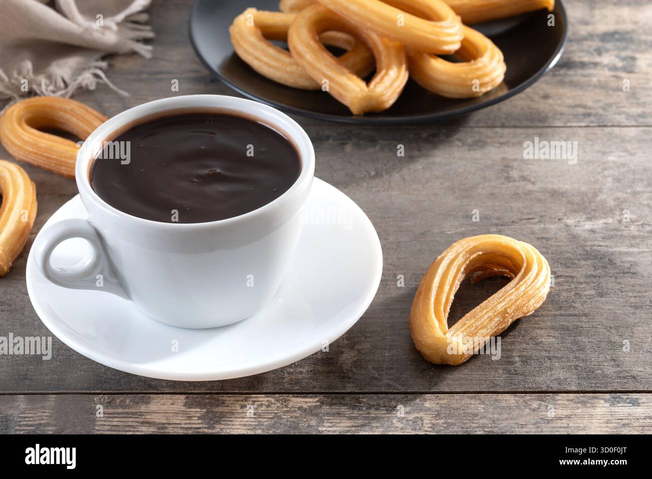 Cioccolata calda spessa in una tazza bianca con churros su un tavolo di legno Foto Stock