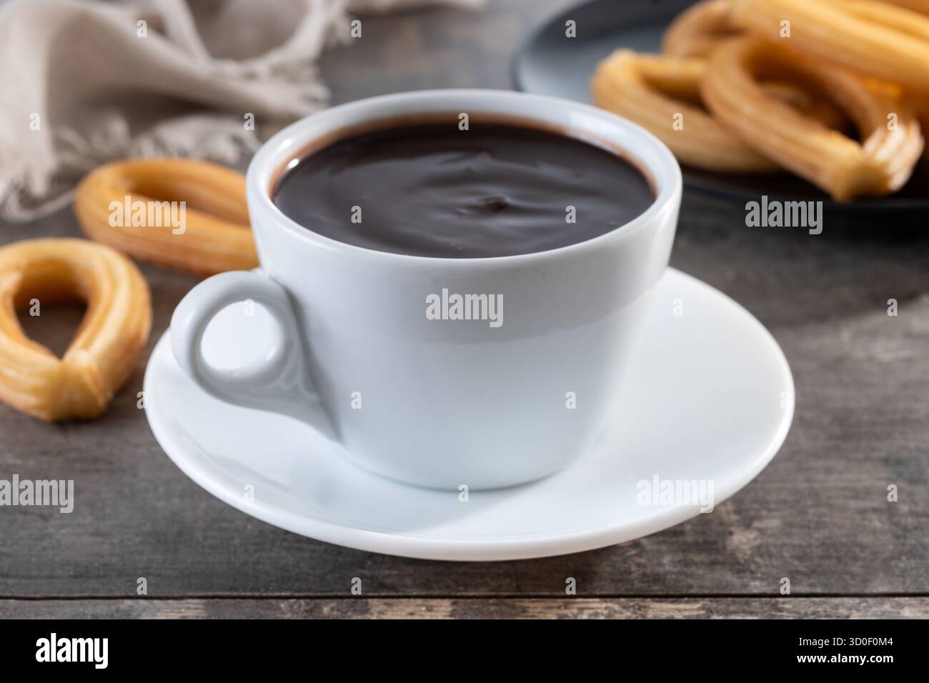 Cioccolata calda spessa in una tazza bianca con churros su un tavolo di legno Foto Stock