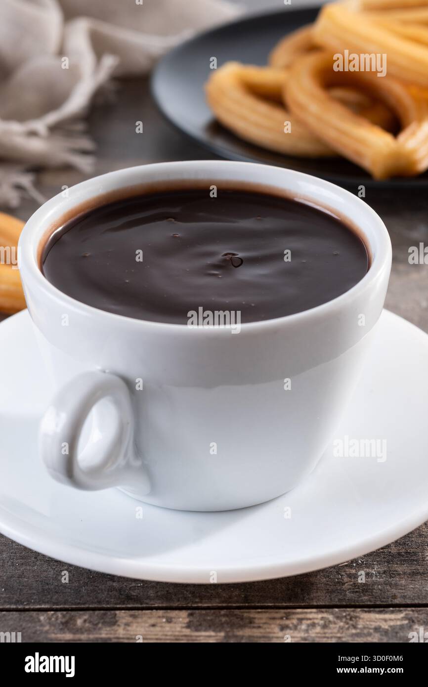 Cioccolata calda spessa in una tazza bianca con churros su un tavolo di legno Foto Stock