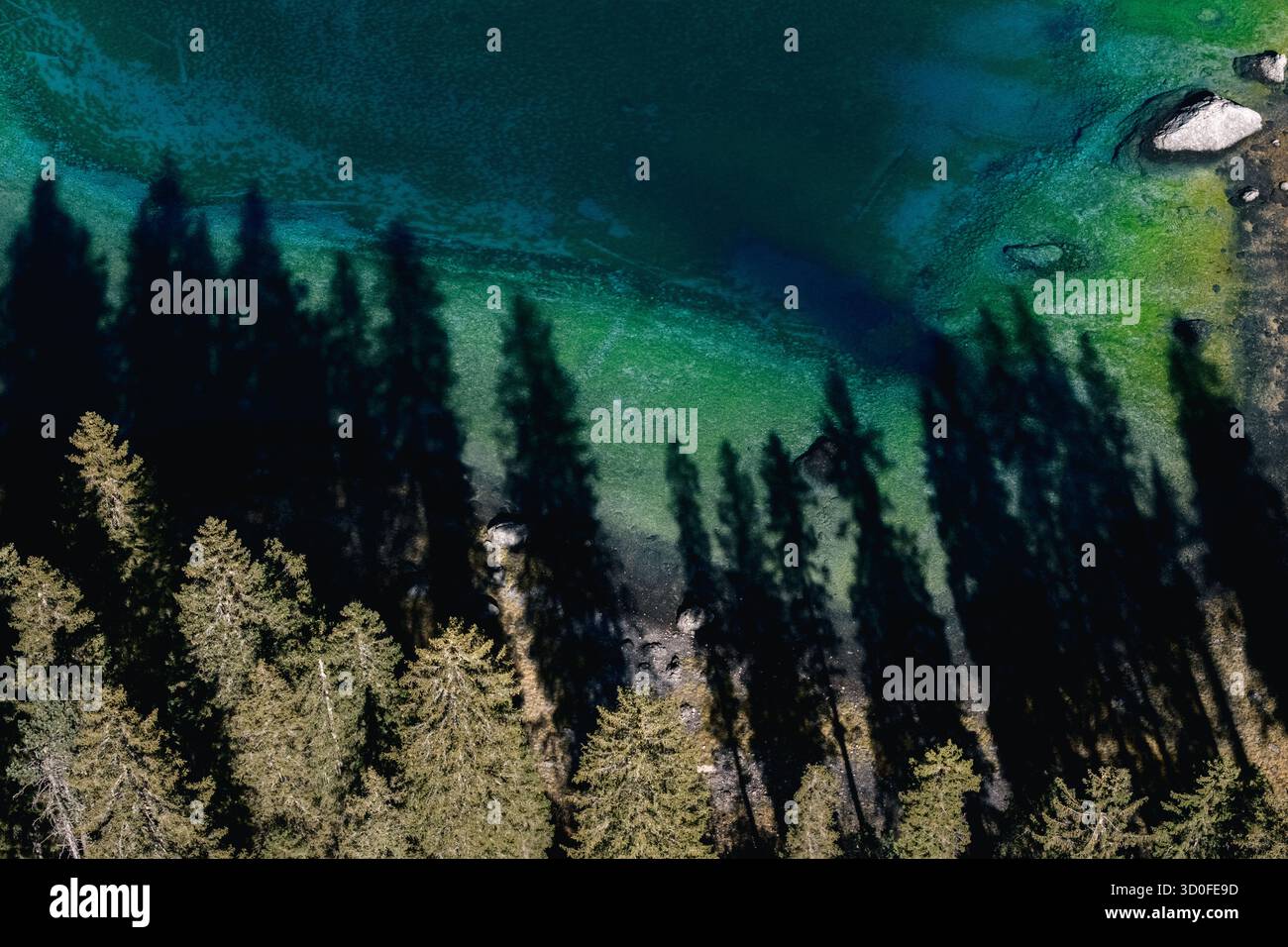 Vista aerea dell'ipnotico lago di Carezza, le acque turchesi incontrano le ombre scure della fitta foresta sempreverde circostante, Karersee, Trentino-alto Adige, Italia. Foto Stock