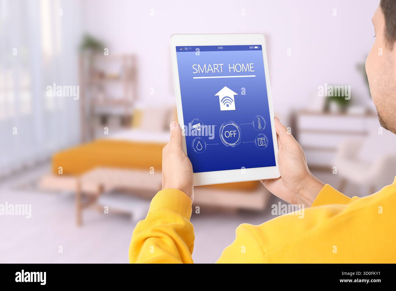 Uomo che utilizza un'app per la casa intelligente su un tablet per controllare le caratteristiche della casa e per un primo piano Foto Stock