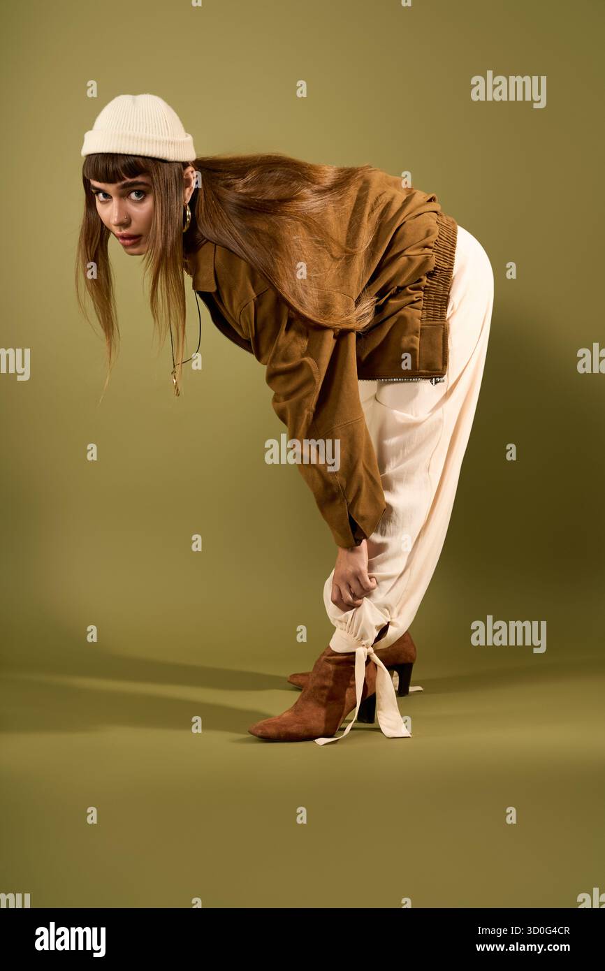 Una bella giovane donna adatta il suo outfit elegante, incarnando la creatività e la sicurezza della moda. Foto Stock