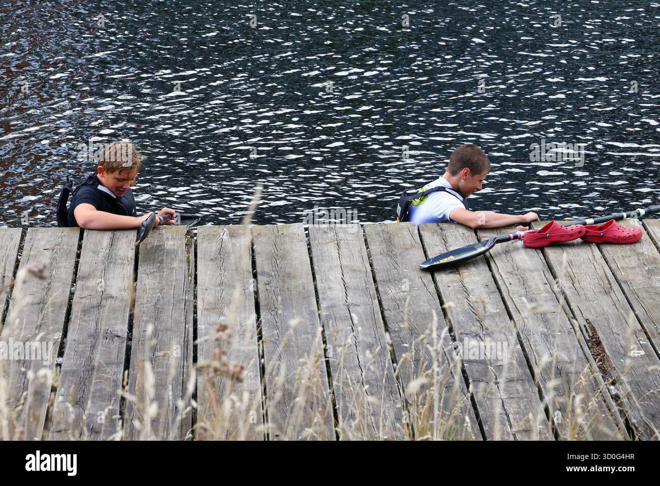 I ragazzi in kayak si appoggiano contro un molo di legno sul fiume Foto Stock