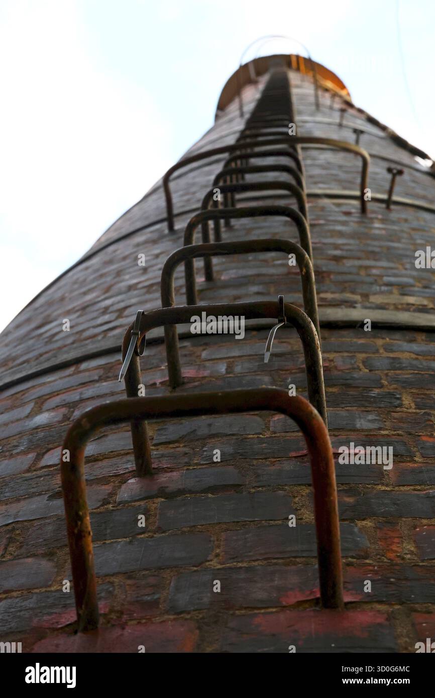 Uno scatto dal basso che mostra un camino in mattoni con una scala che conduce alla luce. Foto Stock