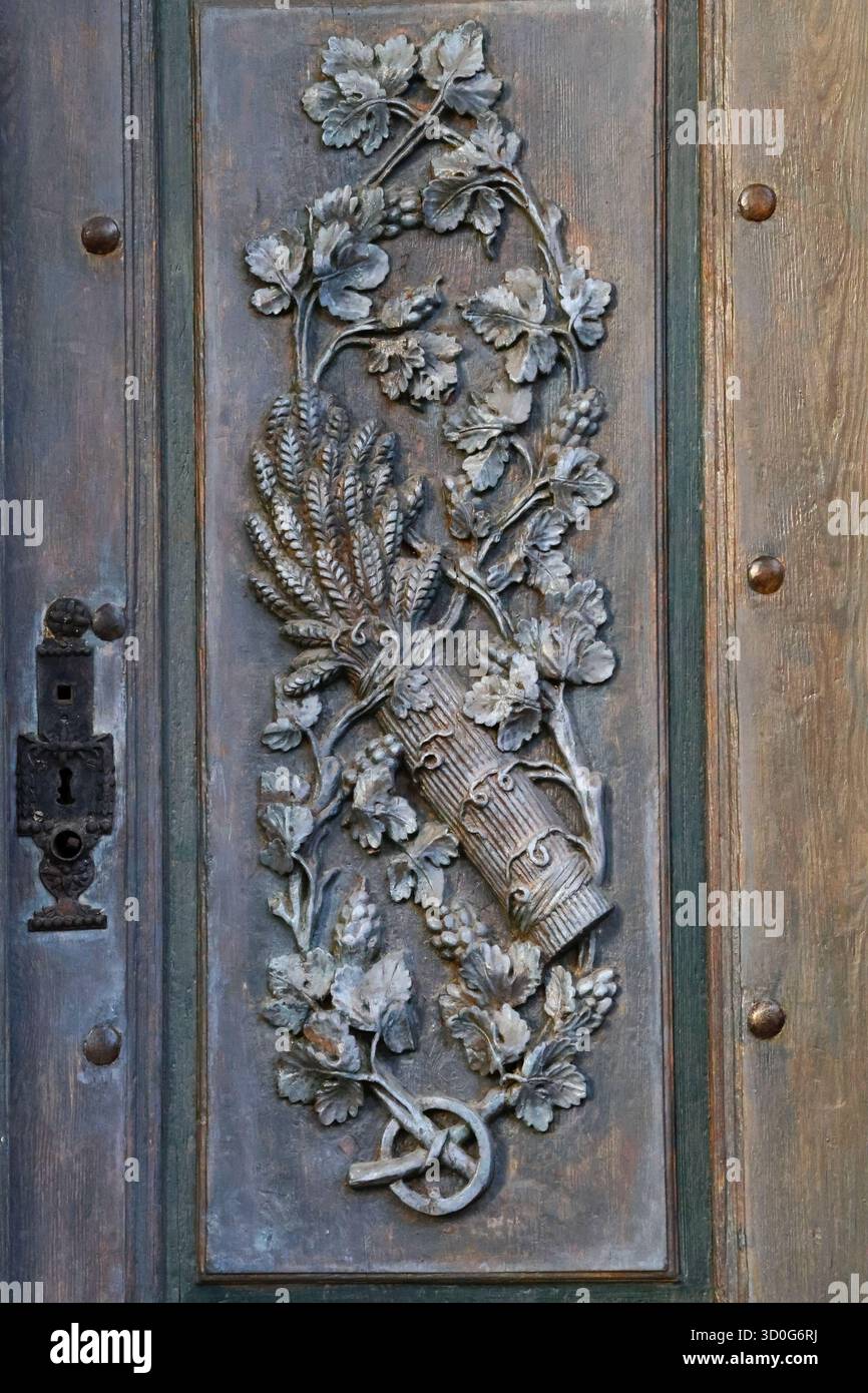 Bassorilievo decorativo in metallo raffigurante piante su una vecchia porta in legno con serratura metallica Foto Stock
