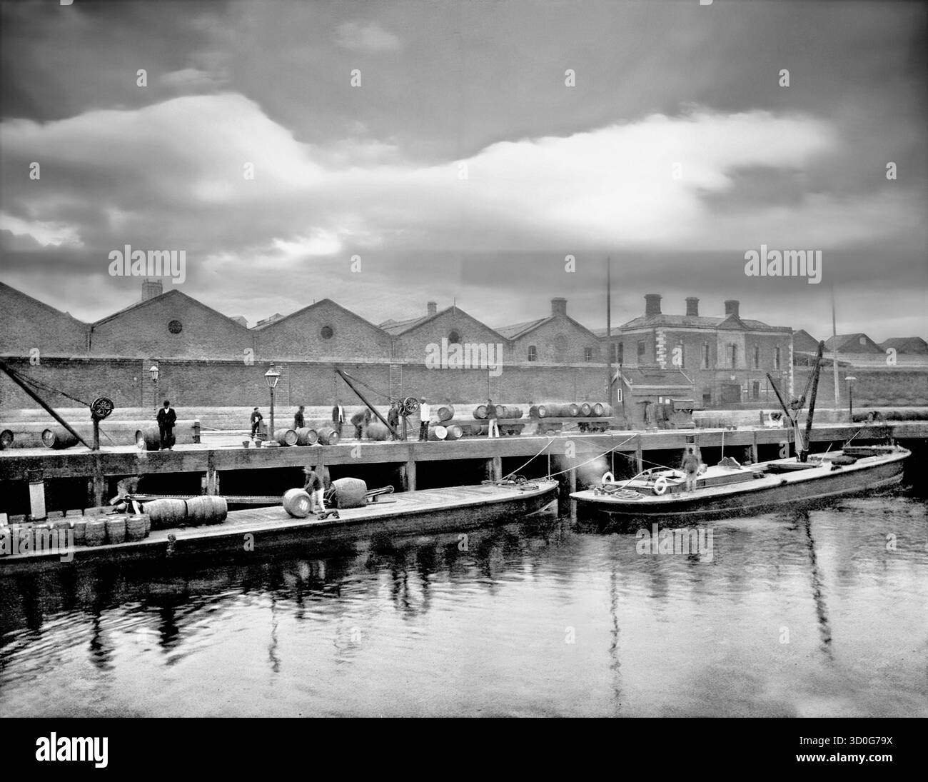 Una vista di fine 19th ° secolo dei lavoratori che caricano barili Guinness su chiatte ormeggiate alle banchine sul fiume Liffey, Dublino, Irlanda. Quando St. James's Gate Land è stato affittato a Arthur Guinness a $ £45 all'anno per 9.000 anni, la fabbrica di birra fondata nel 1759 è stata la casa di Guinness da allora. È diventata la più grande birreria d'Irlanda nel 1838 e la più grande al mondo entro il 1886, con una produzione annua di 1,2 milioni di barili. Foto Stock