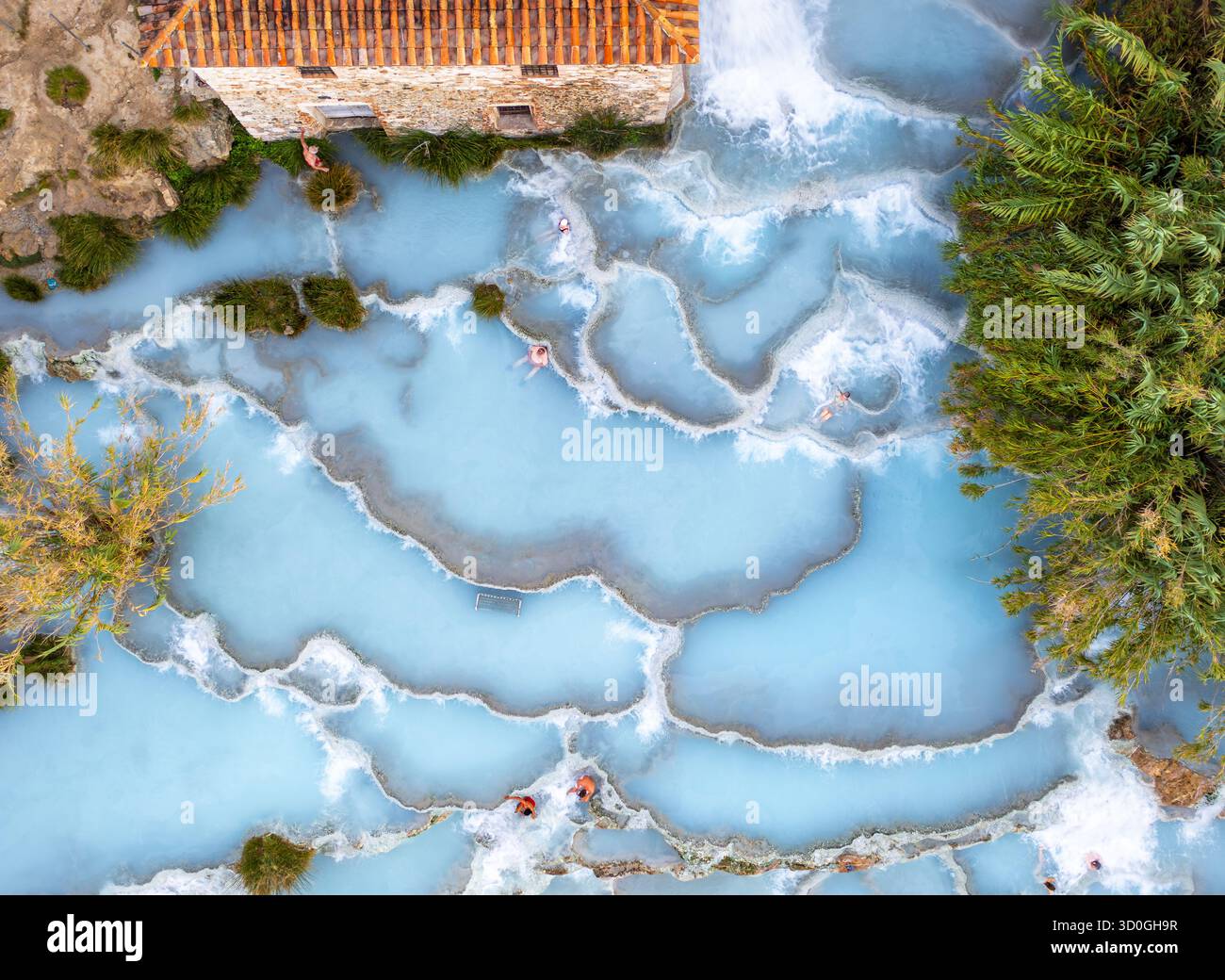 Vista aerea delle acque azzurre che scendono dalle piscine terrazzate di Saturnia, dove le persone si rilassano tra i torrenti che scorrono, Manciano, Toscana, Italia. Foto Stock