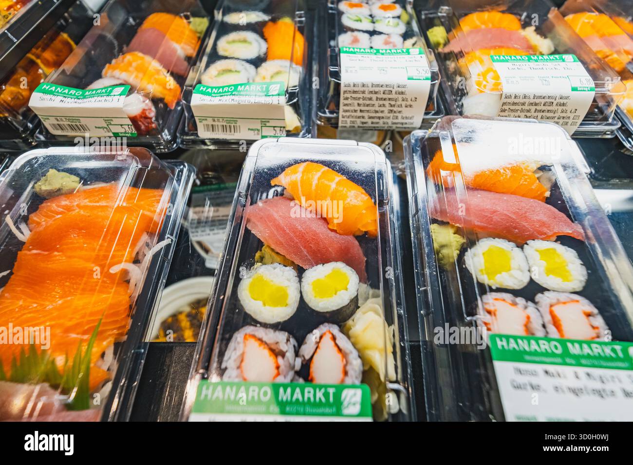 Uno scaffale del supermercato che espone vari piatti di sushi preconfezionati in contenitori di plastica Foto Stock