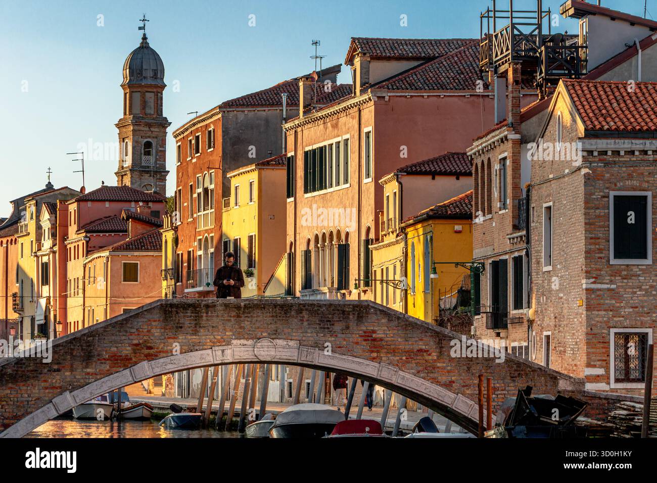 Un uomo in piedi sul Ponte San Trovaso nel sestiere Dorsoduro di Venezia, Italia Foto Stock