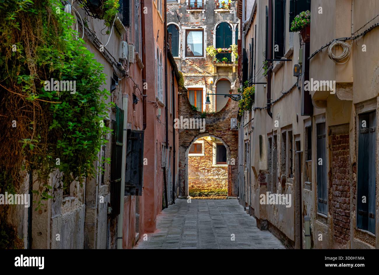 Uno stretto passaggio con un edificio illuminato dalla luce del sole nel sestiere di San Polo di Venezia Foto Stock