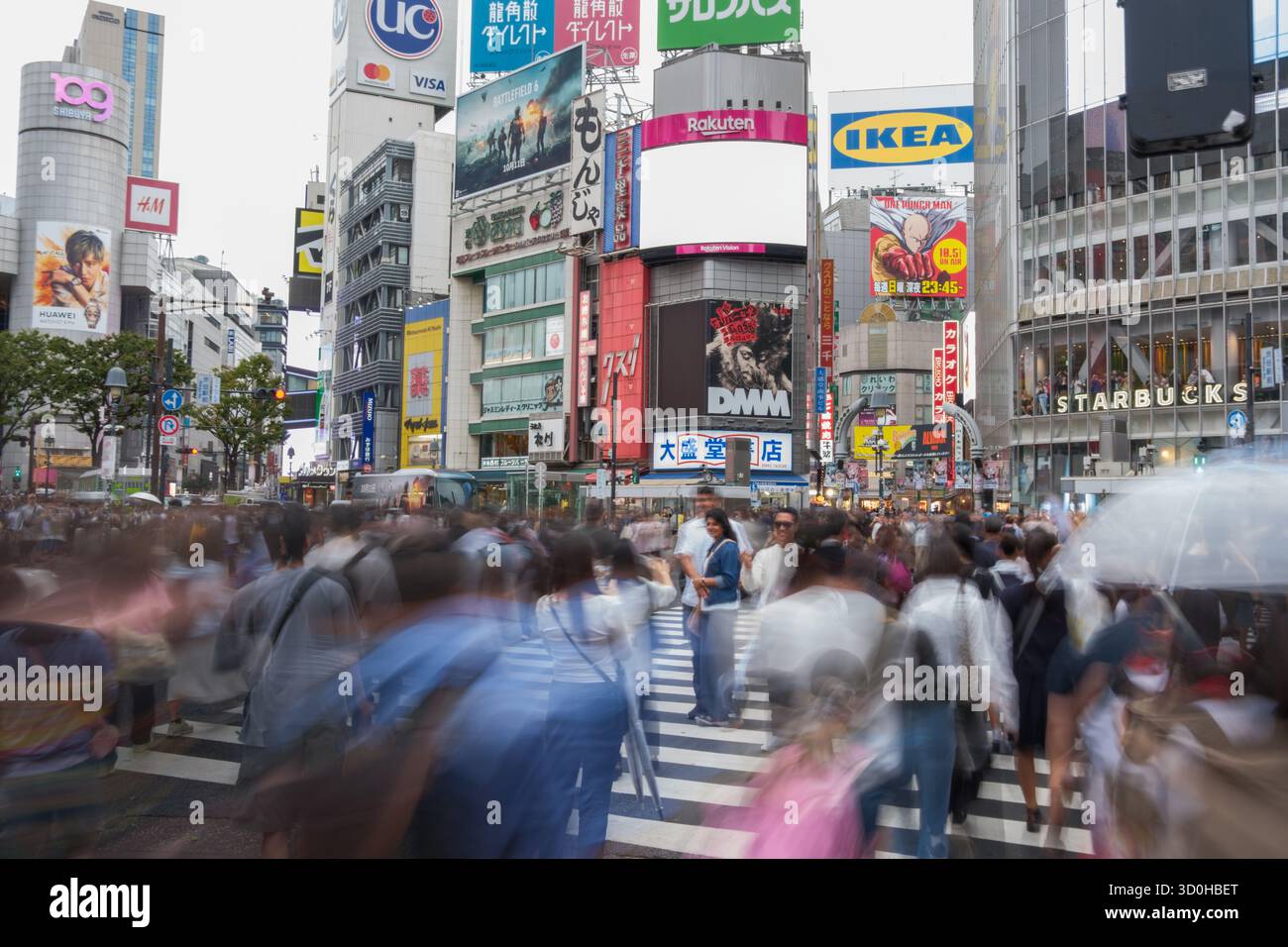 Tokyo, Giappone - 1 ottobre 2025: Vista dell'iconico incrocio di Shibuya, dove figure sfocate si innalzano attraverso le strisce zebrate sotto un vivace arazzo di cartelloni, un caleidoscopio di energia urbana. Foto Stock