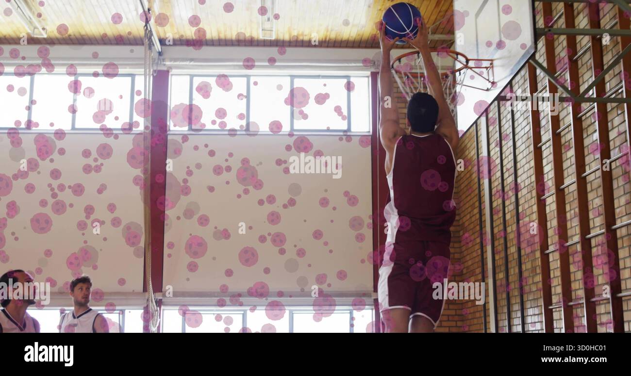 L'atleta in maglia marrone che fa sprofondare il pallacanestro sul bordo della palestra scolastica, copia spazio Foto Stock
