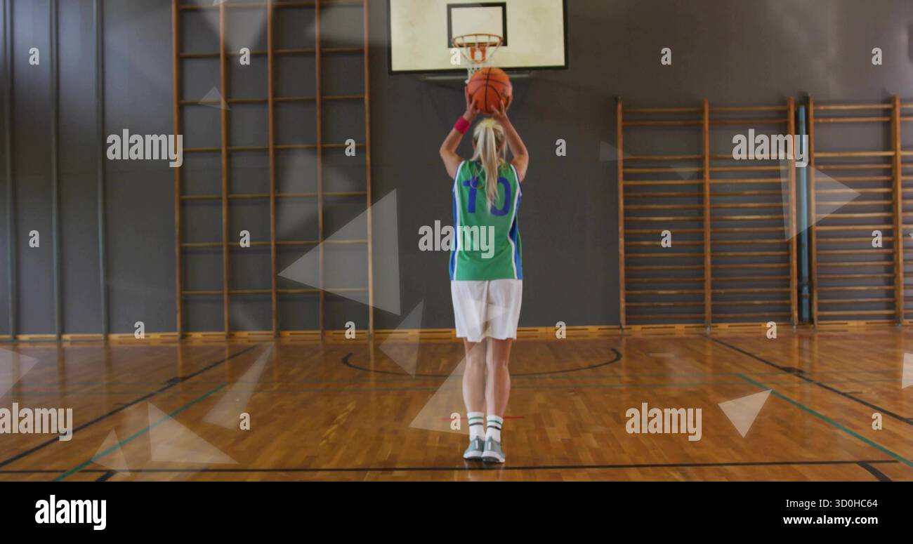 Regge l'atleta di basket in maglia che tira il lancio gratuito nella palestra scolastica con il backboard a cerchio Foto Stock
