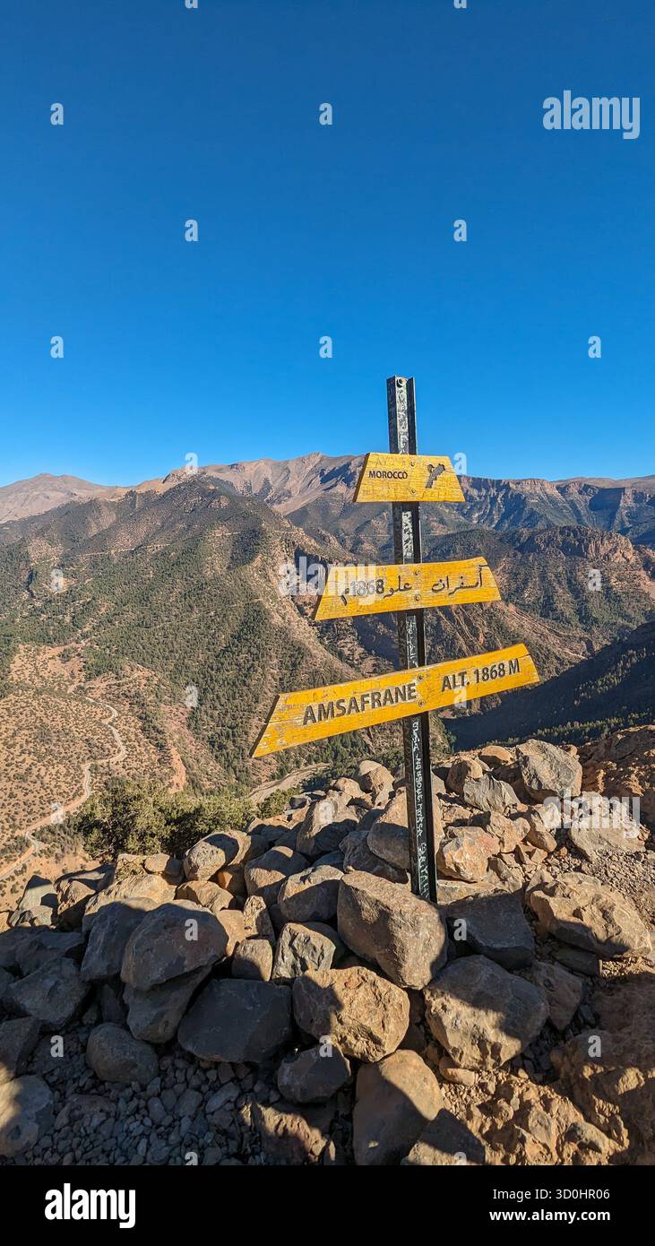 Paesaggio montano panoramico nell'alto Atlante del Marocco con un cartello in legno giallo che segna l'altitudine di Amsafran a 1868 metri. - Immagine stock catturata con smartphone