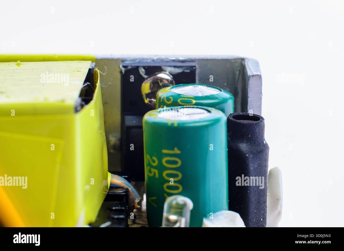 Vista macro del condensatore gonfiato sulla scheda a circuito verde all'interno dell'alimentatore, che mostra il concetto di danni e riparazione. Foto Stock