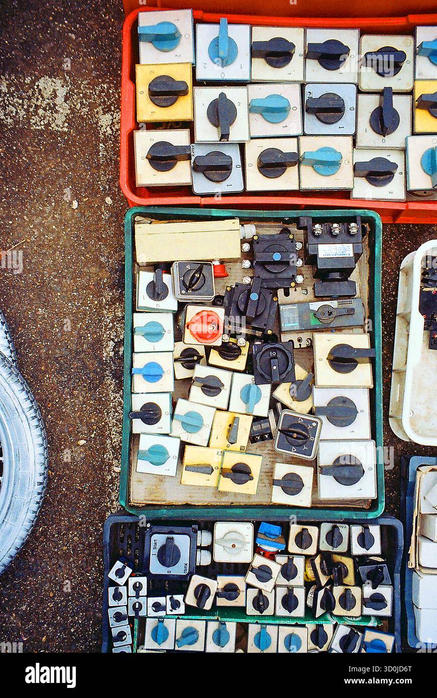 Ripresa analogica di tre casse riempite di interruttori elettrici impilati di varie dimensioni e capacità, sottolineando la ripetizione e lo schema. Foto Stock