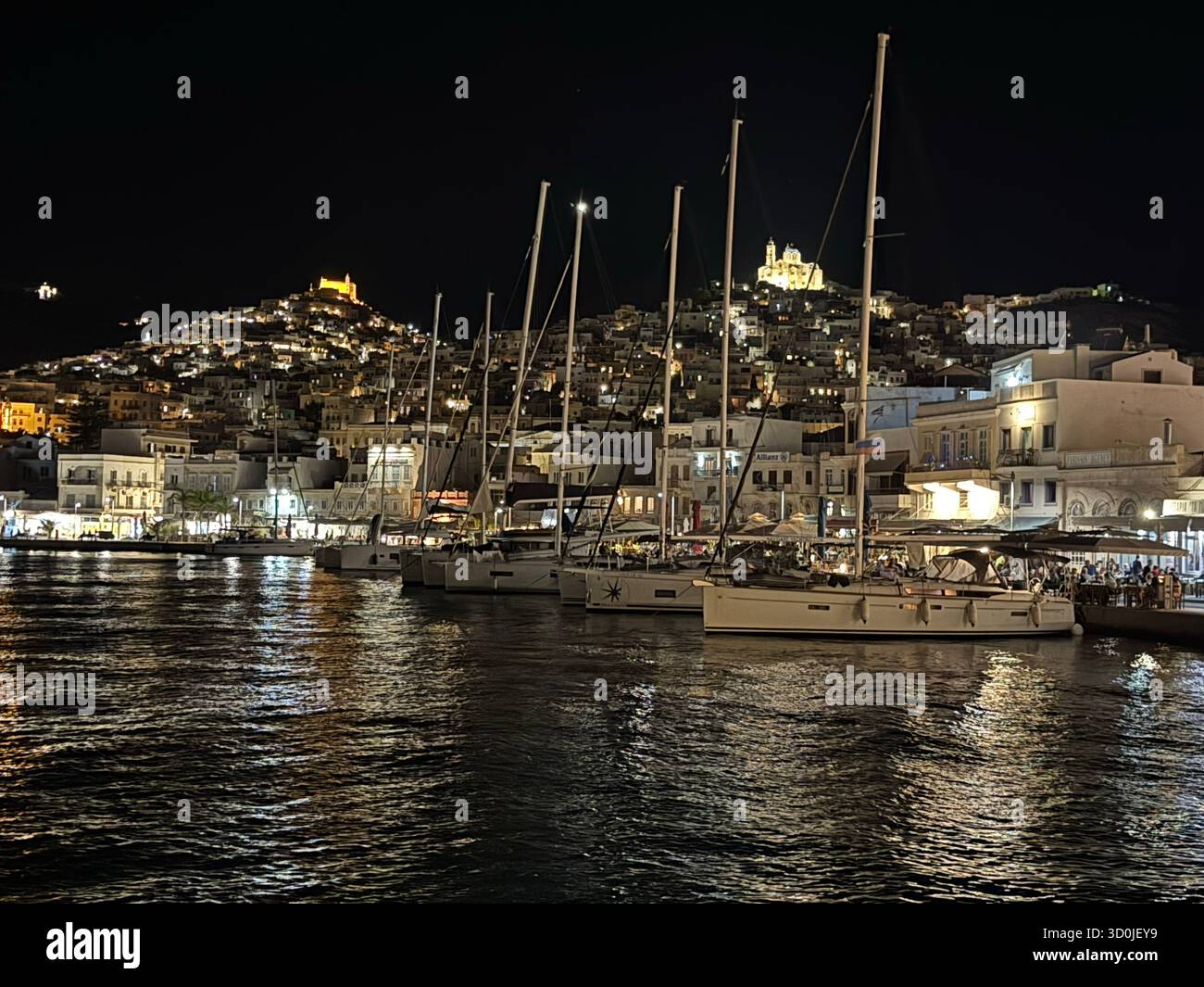 Foto notturna di barche a vela all'ancora nella città portuale di Ermoupoli di notte - isola di Syros, Isole Cicladi, Grecia Foto Stock